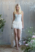 Woman wearing a light blue strapless top and white ruffled high-low skirt.