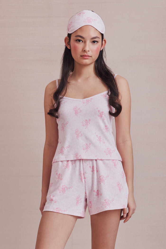 Woman wearing a pink PJ set with a pink sleep mask against a pink background