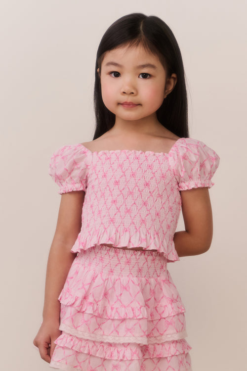Young girl wearing a pink floral dress against a plain background