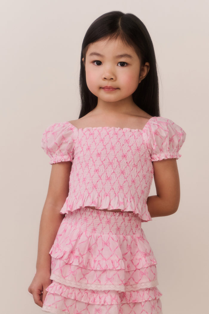 Young girl wearing a pink floral dress against a plain background