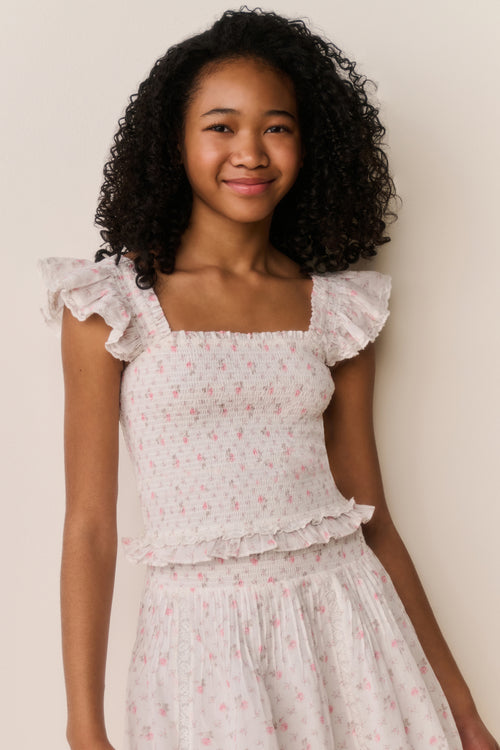Young girl wearing a floral dress against a plain background