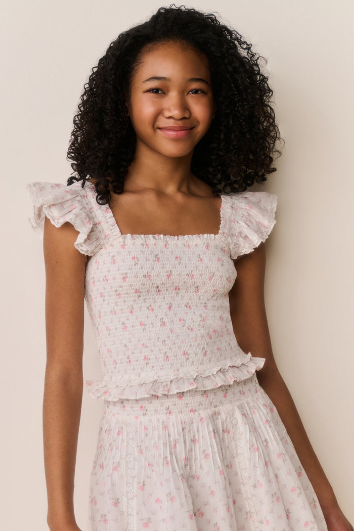 Young girl wearing a floral dress against a plain background