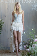 Woman in a striped bustier standing in a garden with white lace, tiered, high-low skirt.