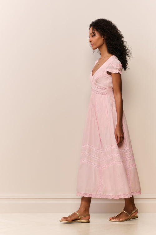 Woman wearing a pink dress against a white wall