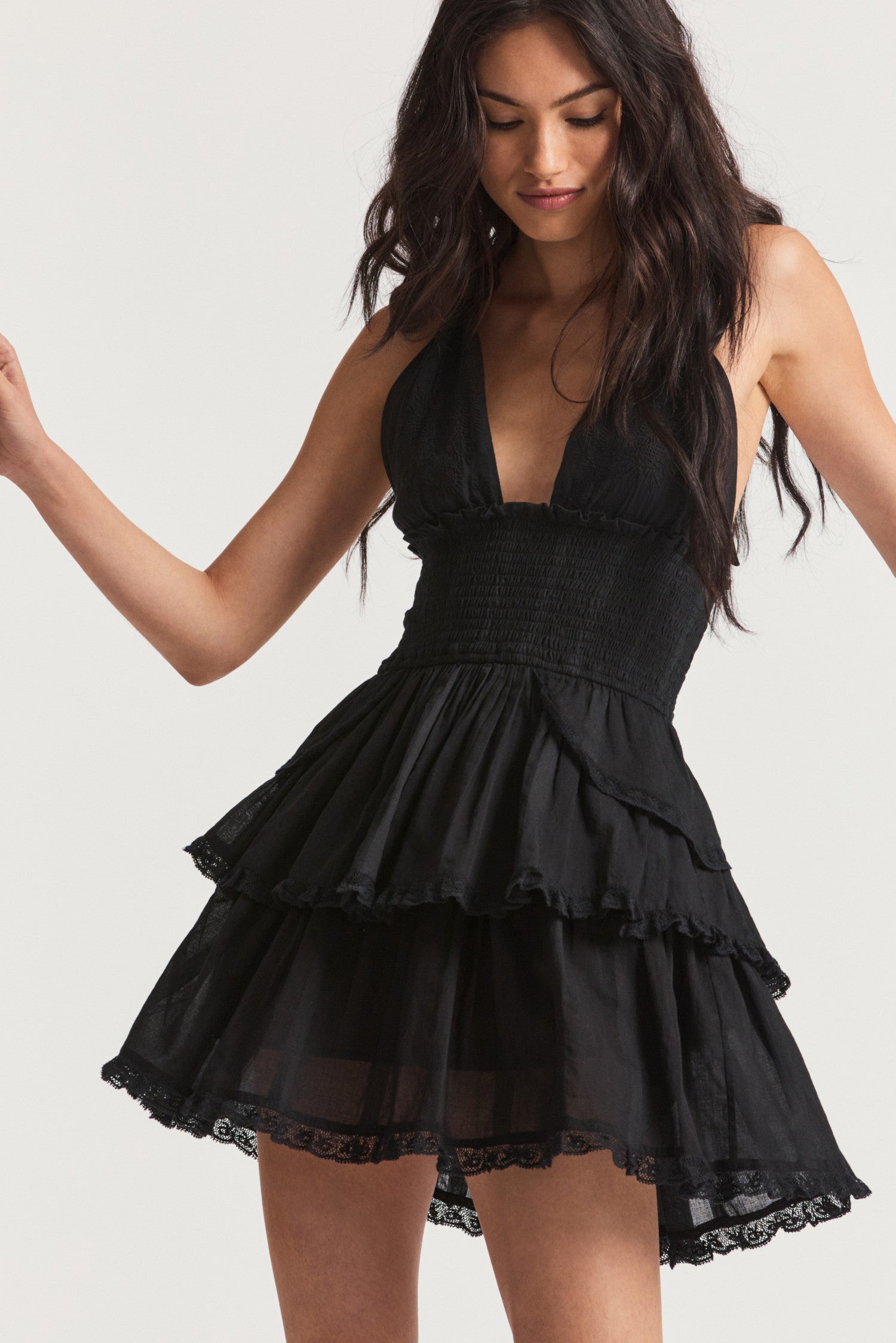 Black mini dress with custom dobby striped cotton with all-over botanical embroidery. This low-cut convertible halter, with piping at the neckline, ties in a generous bow at the neck and can be crossed at front. Below a wide smocked waistband, the skirt flares to smaller details at the hips and two scalloped tiers with schiffli cutwork.
