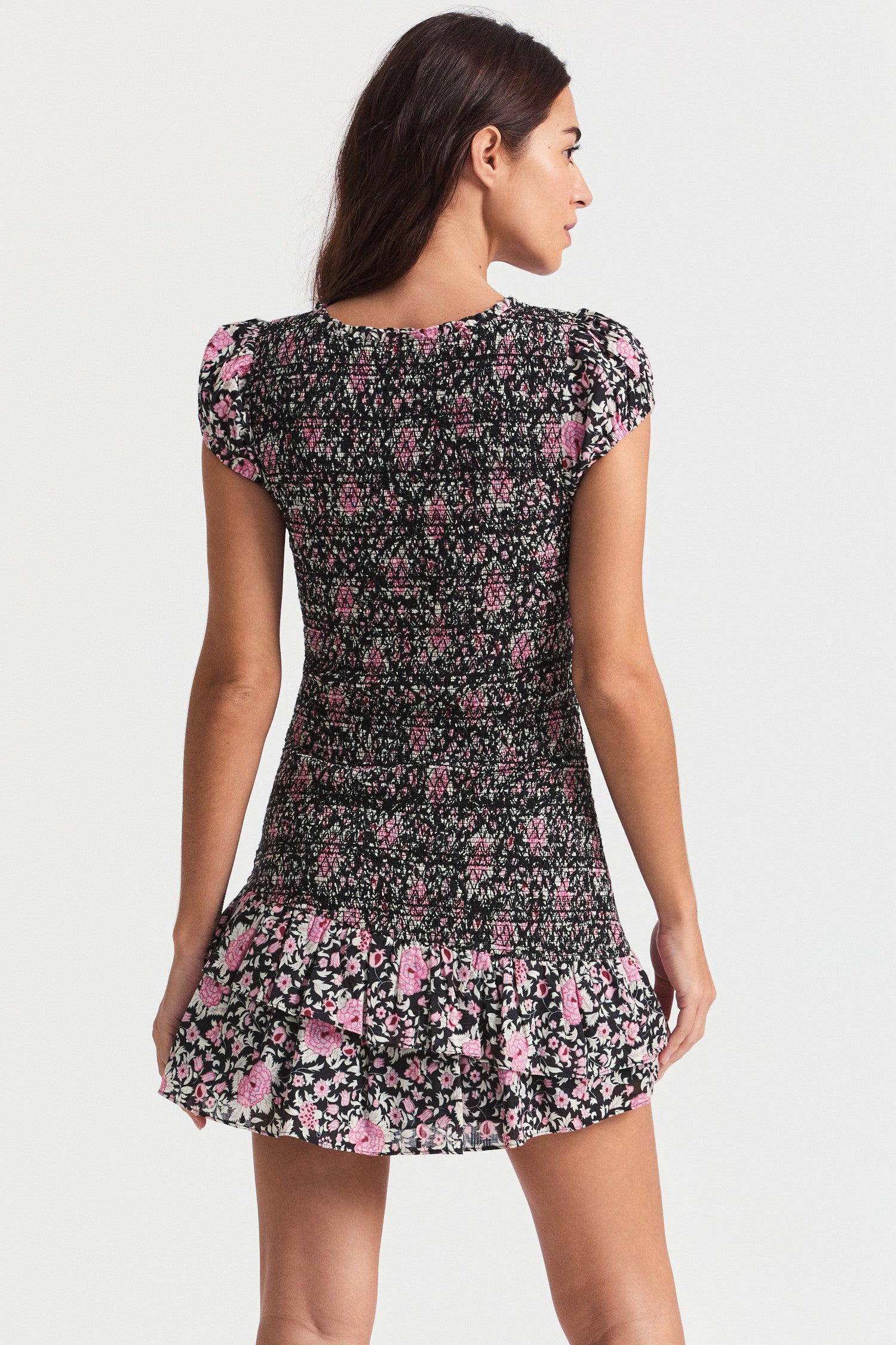 Black mini floral print dress. With short ruffle-trimmed v-neck, a completely smocked bodice, gathered at mid-bust, and part puffed sleeves. At bottom, the asymmetrical skirt flares to two layered flounces.