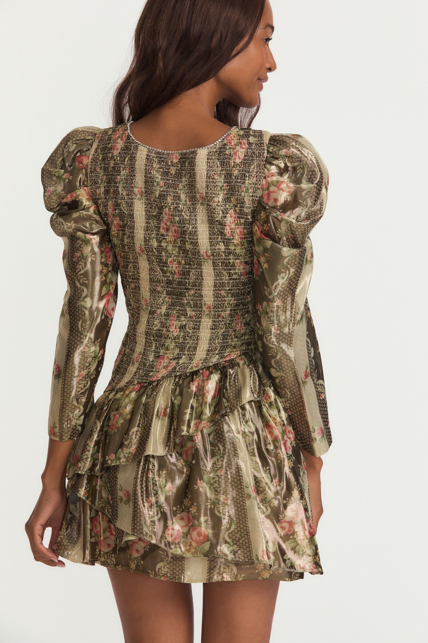 Green and floral mini dress with a printed lurex lame fabric the dress features a smocked bodice, elegant mutton sleeves with shirring at the shoulders that taper into a clean opening, and an asymmetrically tiered skirt. 