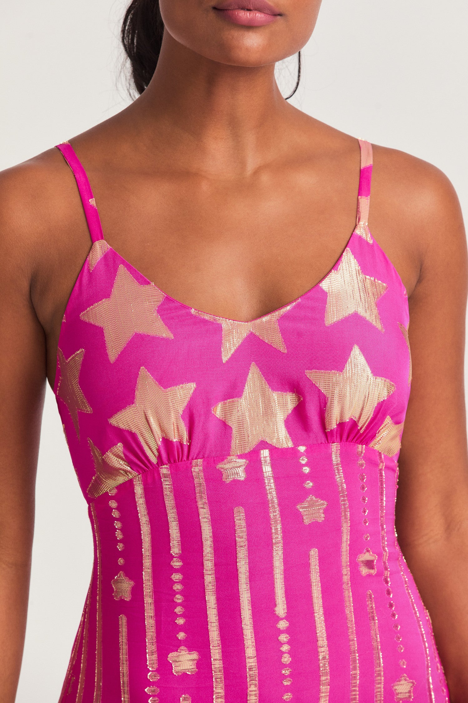  Pink maxi slip dress with metallic gold star detailing with vertical falling stars contrasting along the skirt. In a soft viscose fabric with strap detail at the back that allows you to tie the dress and a slit at the wearer’s left. The back waist features elastic to fit your body.