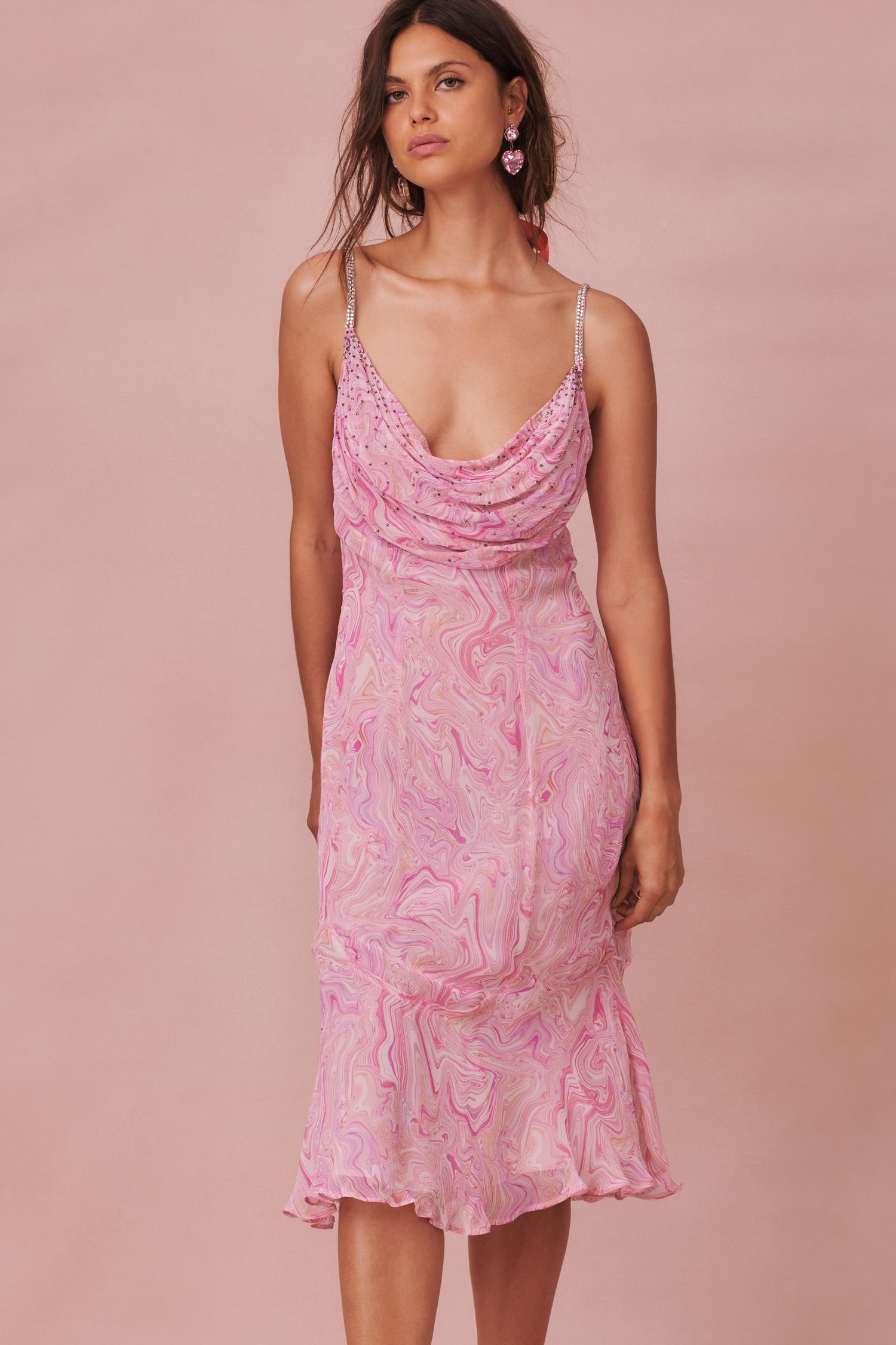 Pink maxi dress with a vibrant print on a luxe velvet fabric. A classic slip dress with a cow neck and drape. The neckline has a spray of crystals, the straps are beaded and the skirt has a flirty sweep.