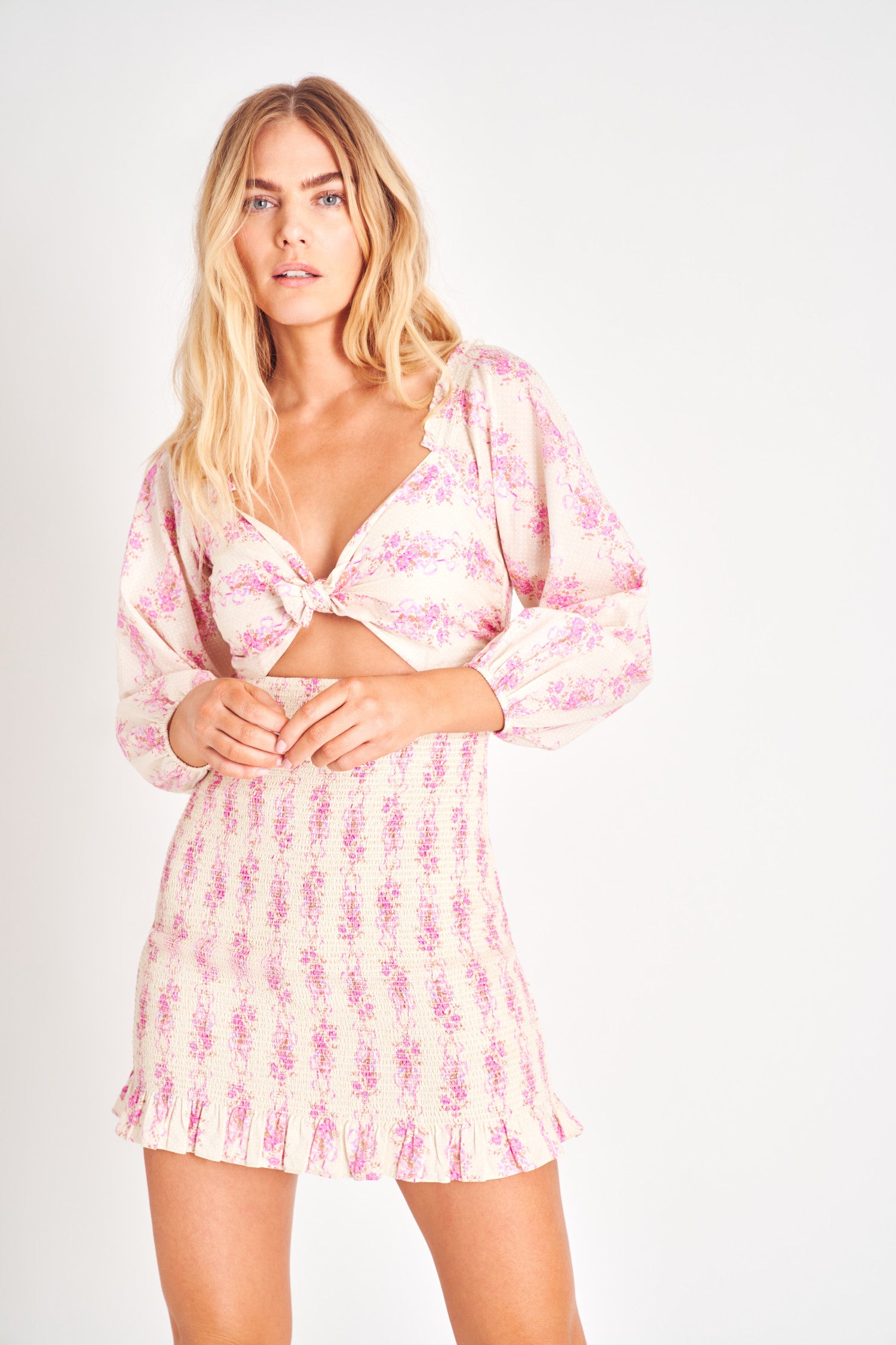 Pink floral long sleeve mini dress with a wrap tie top and a smocked skirt.