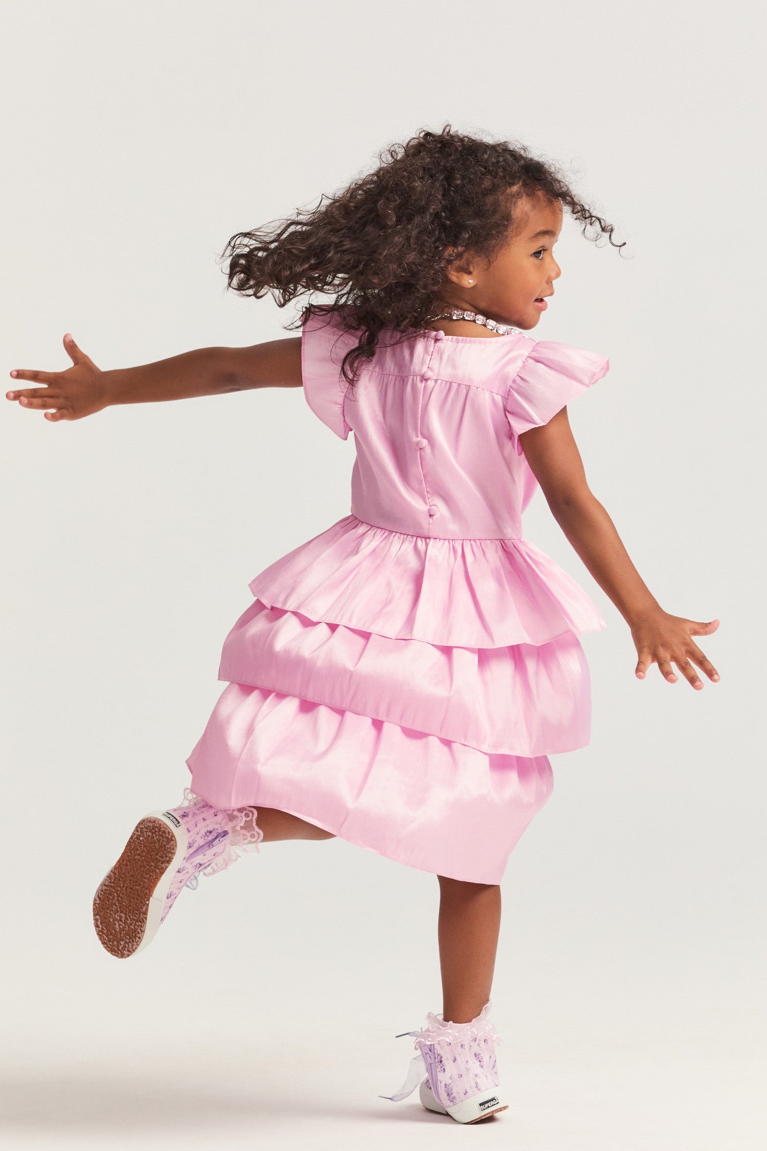 Girls pink dress with nylon fabric, and flutter sleeves frame the roomy bodice. An encased elastic waist lets out into a three-tiered ruffle skirt.