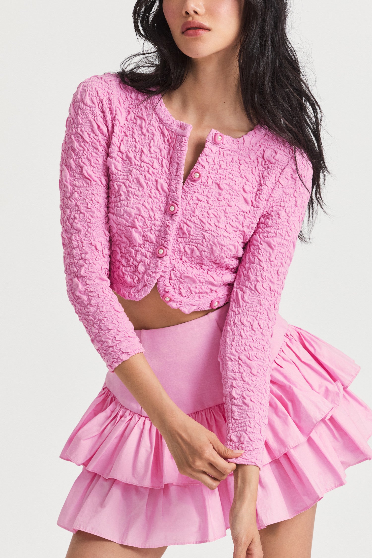 Pink crop cardigan in jacquard fabric that gives a scrunchie and textural fabric. Finished with functional center front buttons.