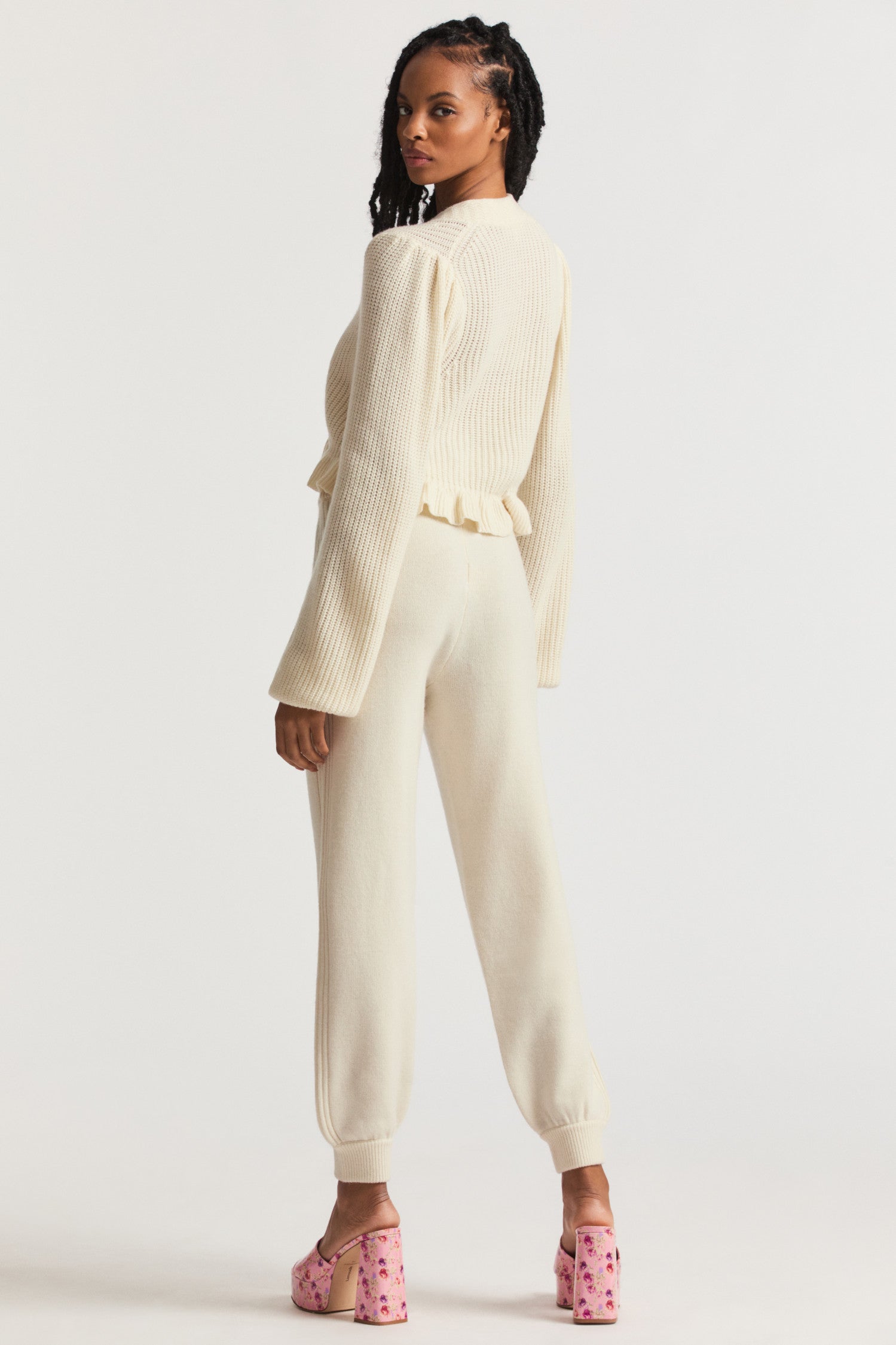 Cream pants made of cashmere fabric feature tuxedo stripe stitching along the sides and a drawstring waistband for easy wear.