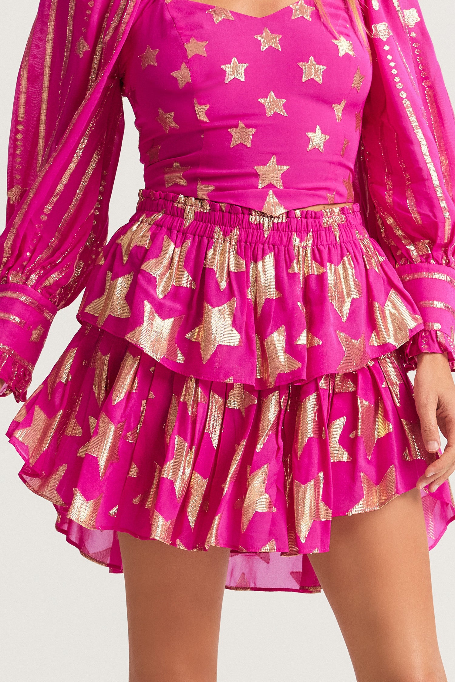 Bright pink mini skirt in viscose fabric with metallic gold star detailing. The two-tiered short skirt, with an elasticated waistband and shirred flounces. 