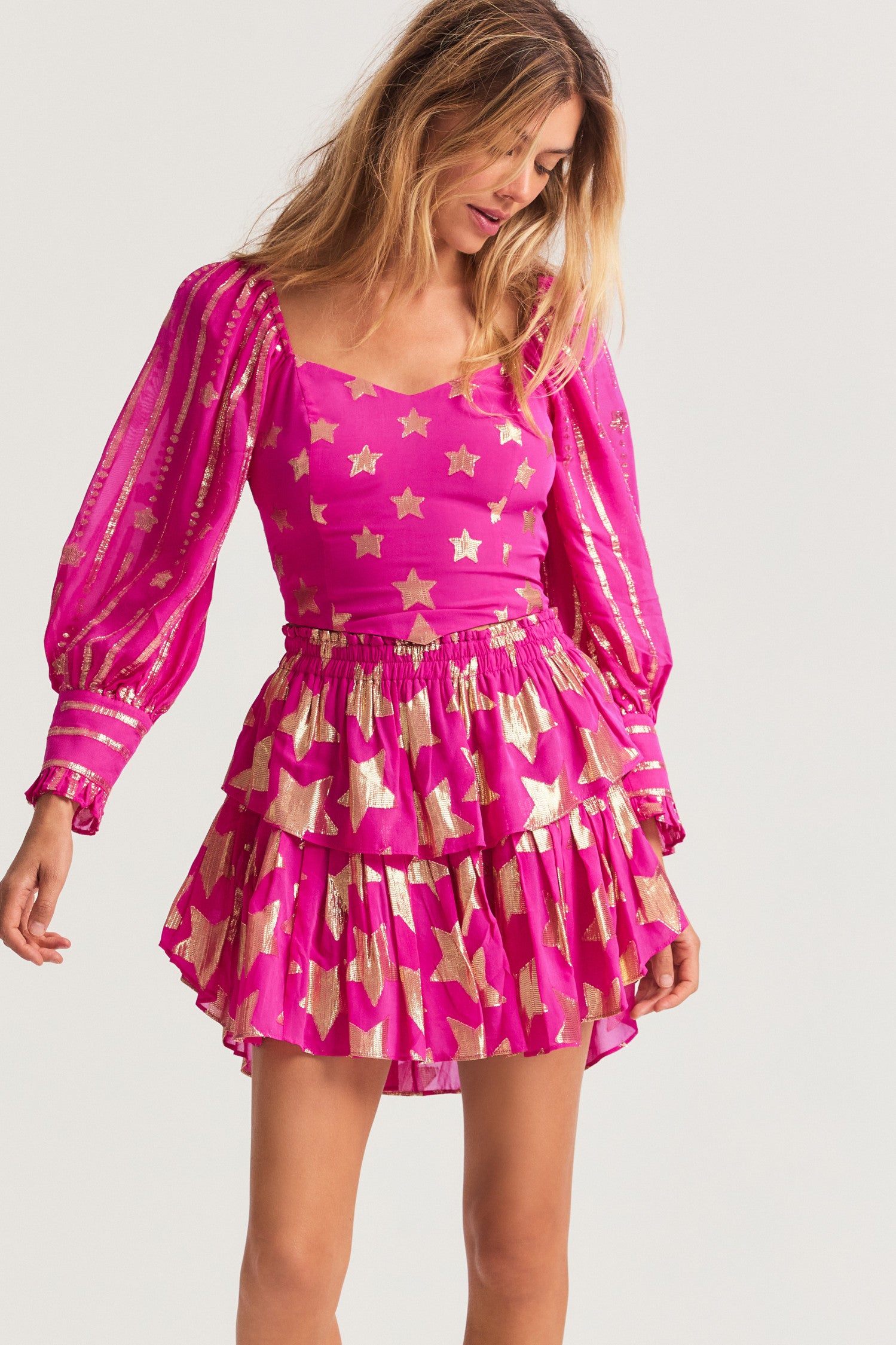 Bright pink mini skirt in viscose fabric with metallic gold star detailing. The two-tiered short skirt, with an elasticated waistband and shirred flounces. 
