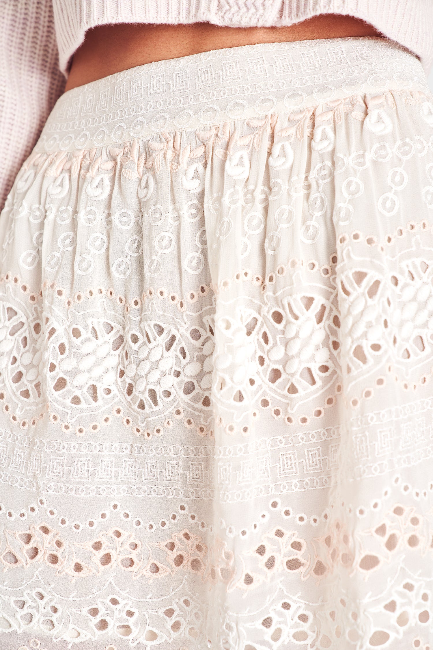 Cream mini skirt with eyelet and embroidery detailing, featuring an A-line hem.