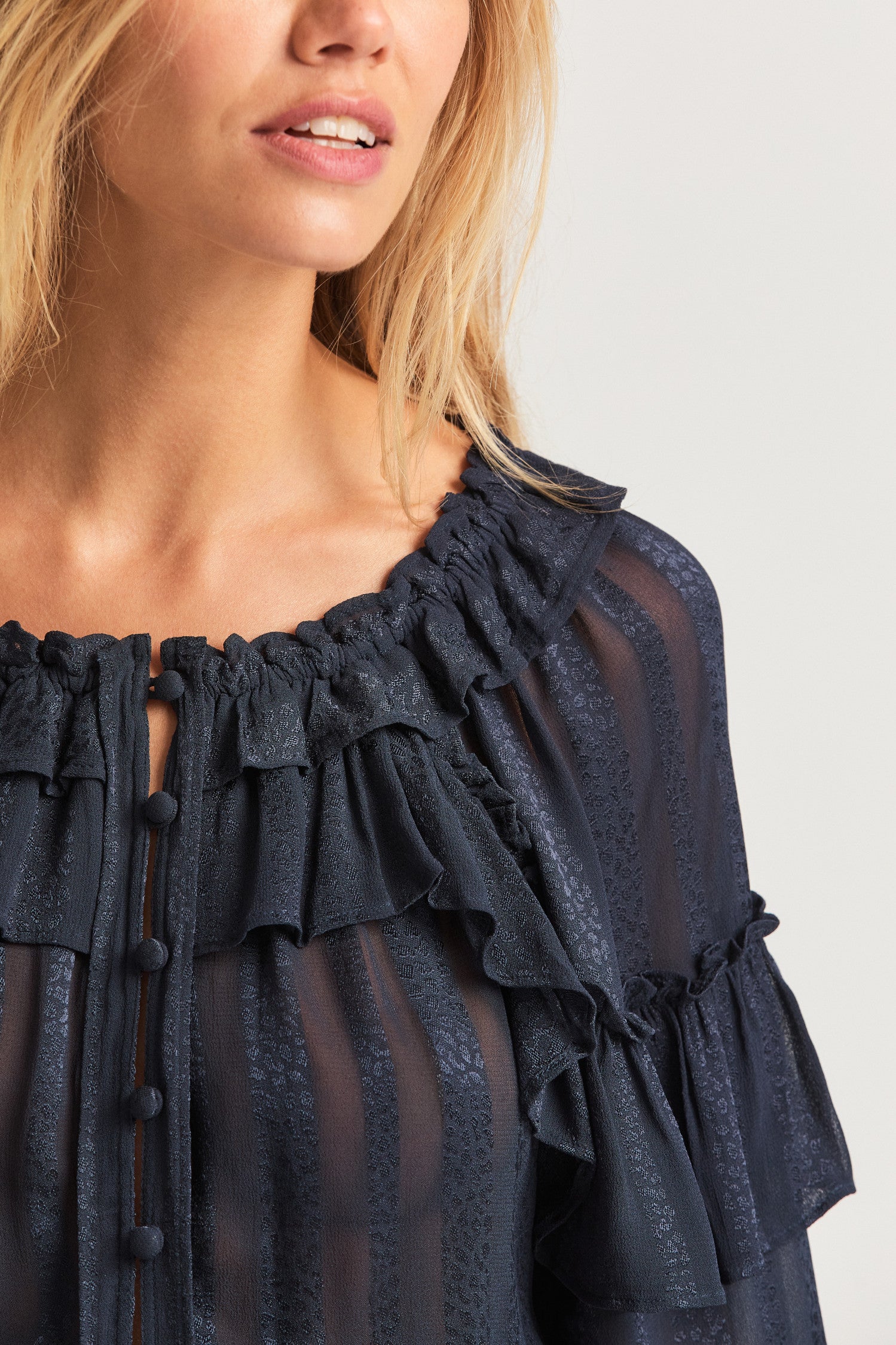 Black long sleeved-top features a striped jacquard fabric, dramatic ruffles all over, an elasticated waist, elastic at the sleeve openings, and a fully functioning center front slit.